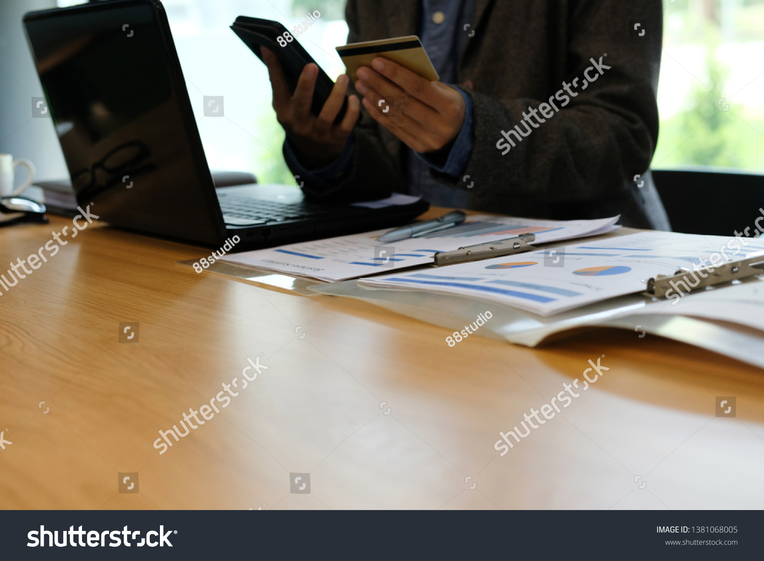 man holding credit card using smart phone for online shopping. businessman purchase product from internet, make payment on bank website at workplace #1381068005
