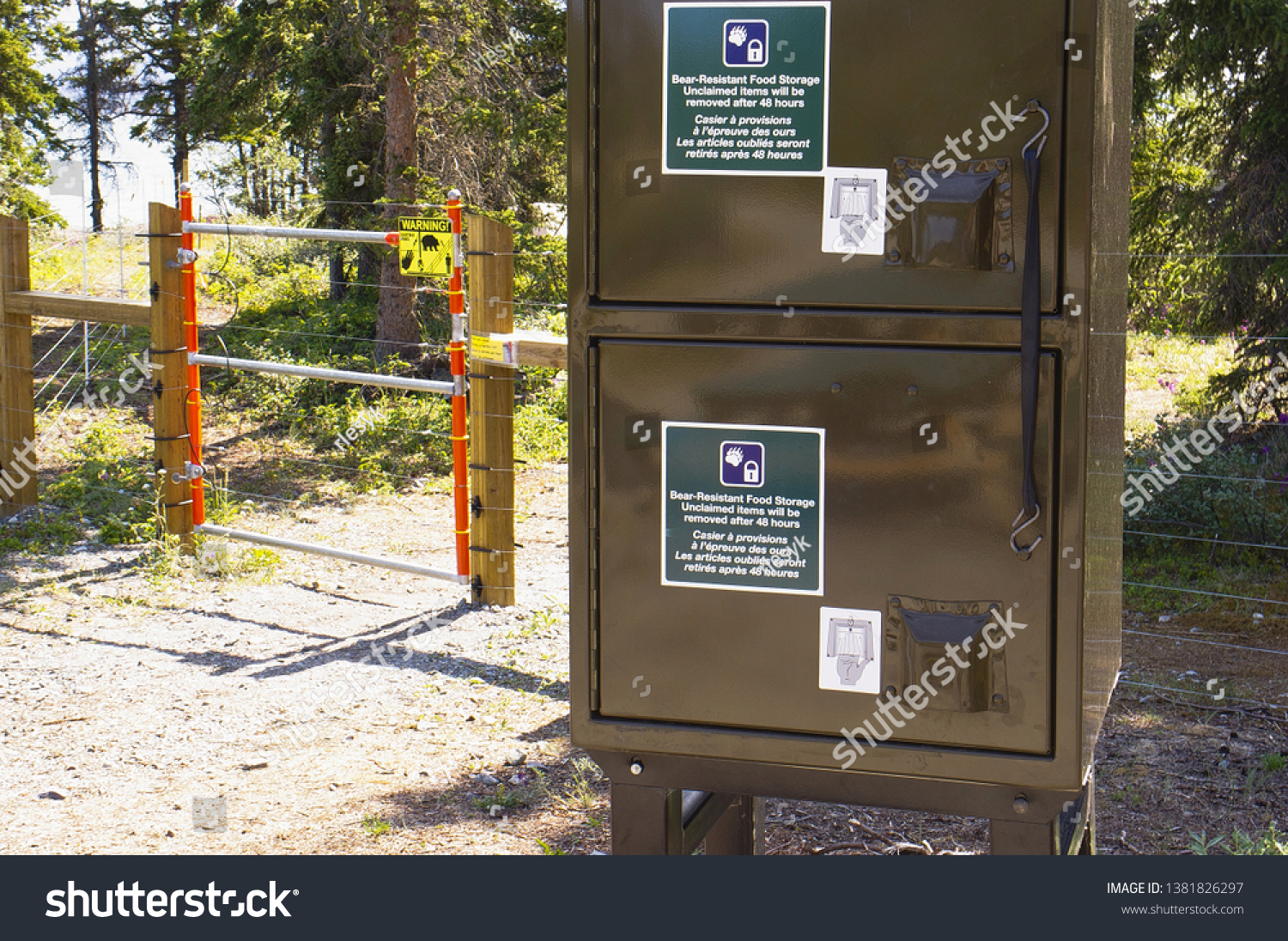 Electric bear fence around tenting area  and bear-resistant food storage lockers at a Yukon campsite, Canada. #1381826297