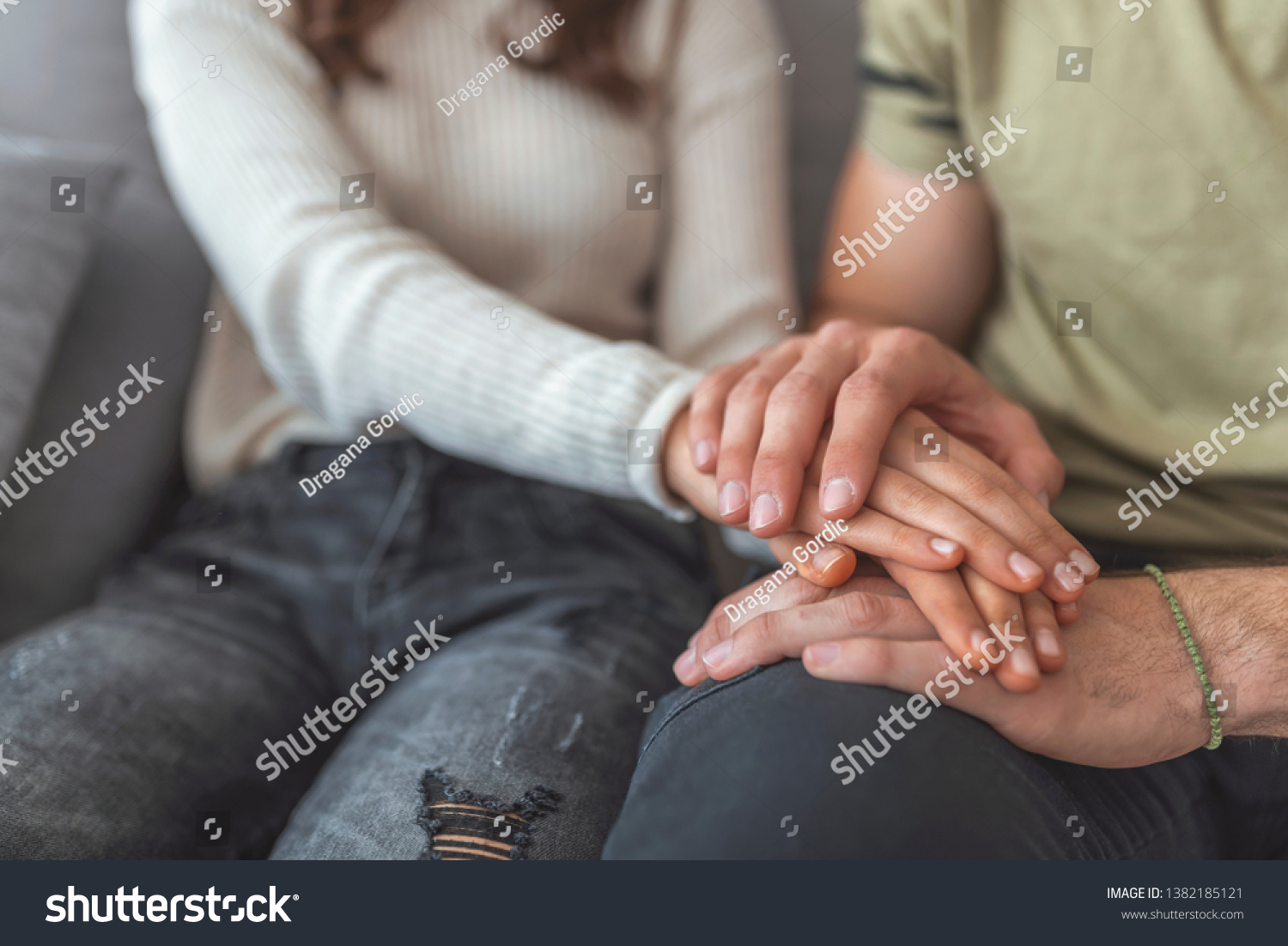Cropped shot of couple holding hands while sitting together at home.Focus on hands. Closeup view of couple holding hands, loving wife supporting or comforting husband ready to help expressing sympathy #1382185121