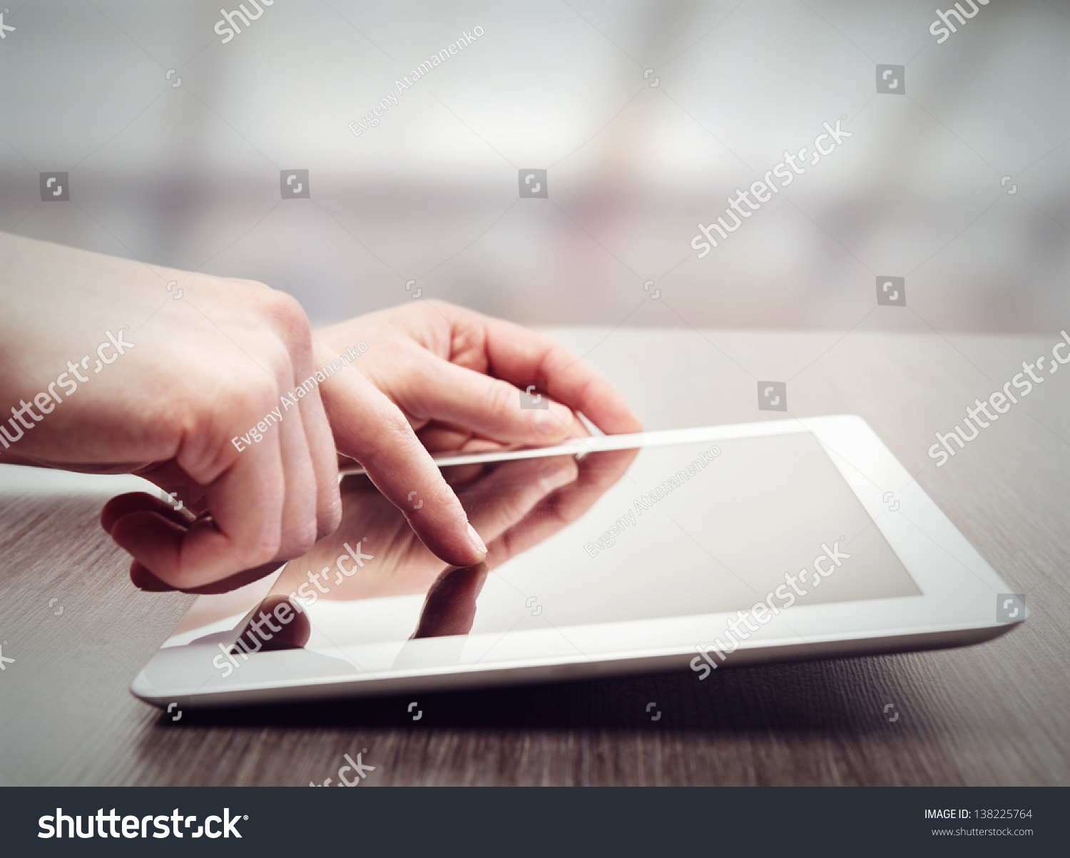 white tablet with a  blank screen in the hands on wooden table #138225764
