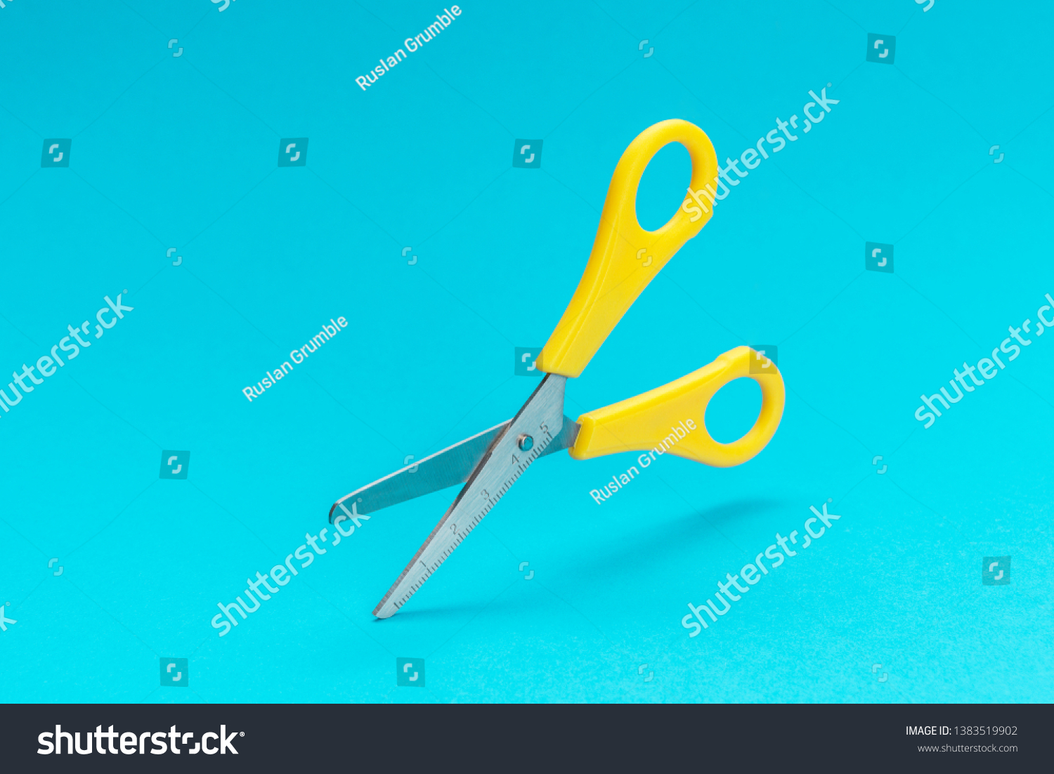 opened yellow scissors over turquoise blue background. conceptual photo of levitating scissors with central composition #1383519902