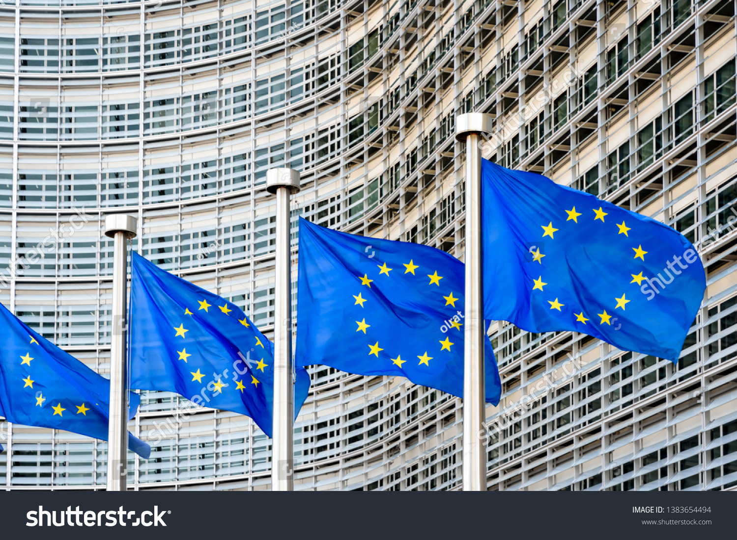 A row of flags of the European Union flying in the wind in front of the Berlaymont building, seat of the European Commission in Brussels, Belgium. #1383654494