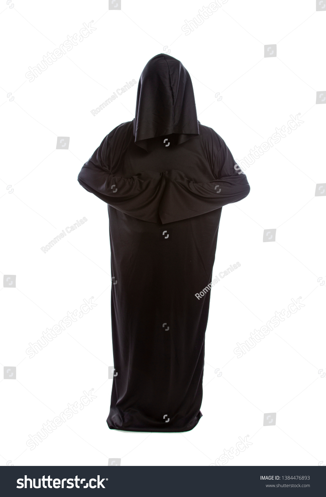 Monk wearing black robes and a hood or a person in a halloween costume of a grim reaper ghost.  The image depicts a priest in traditional or ancient clothing.  #1384476893
