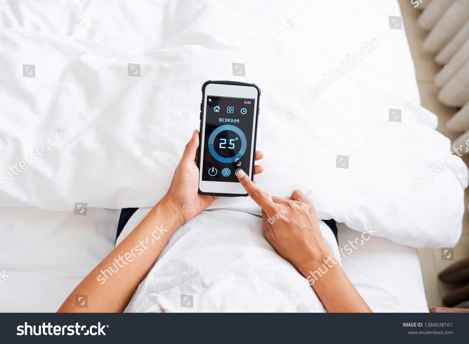 Close-up of woman lying in bed and choosing the normal temperature in bedroom online using smart home application on mobile phone #1384638161