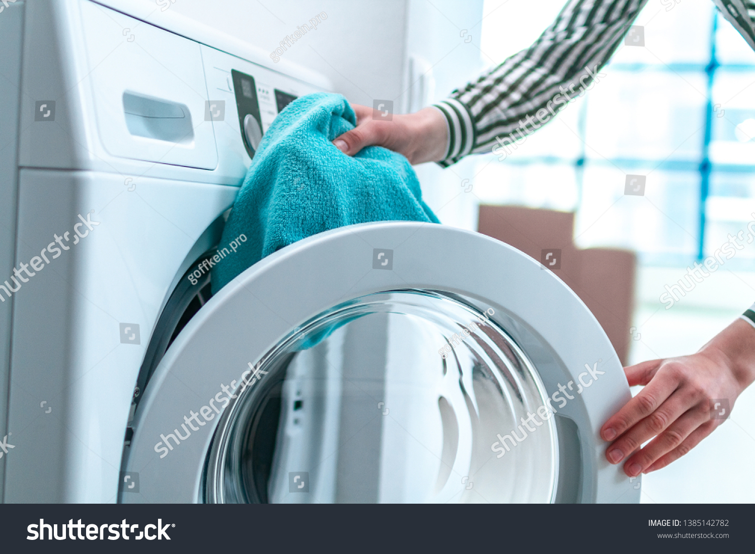 Loading towel, clothes and linen in washing machine. Doing laundry at home. Household chores and housekeeping #1385142782