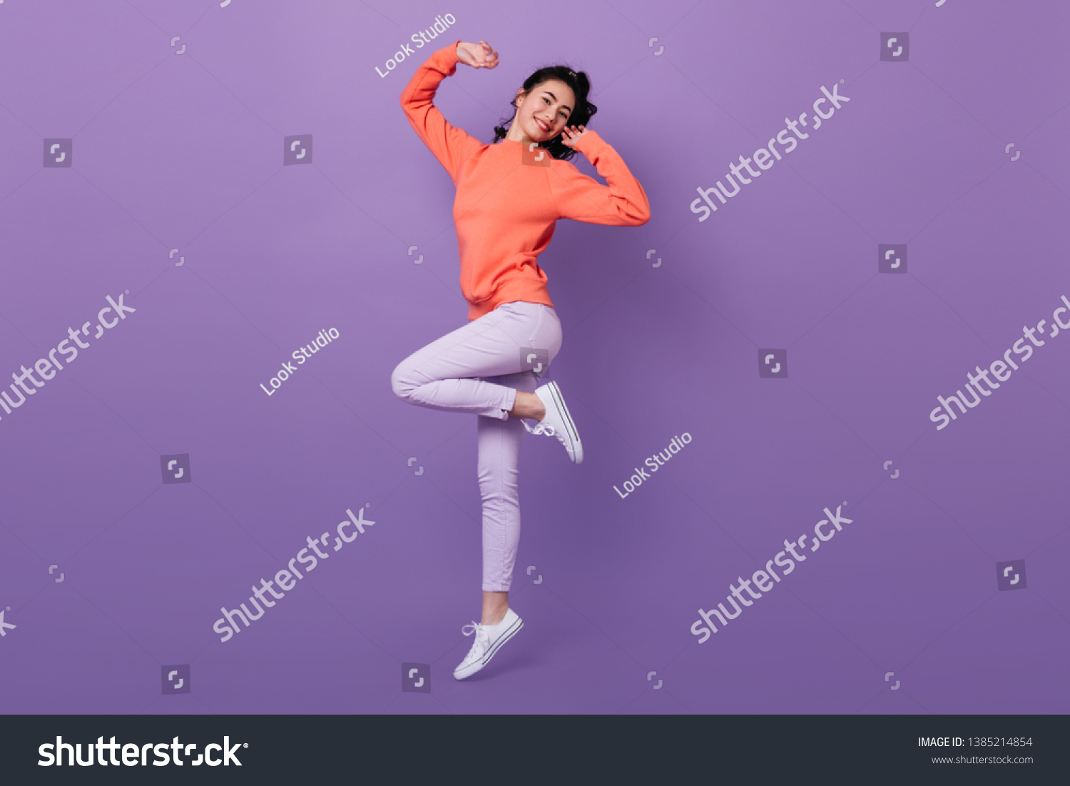 Lovely asian girl standing on one leg. Full length view of attractive stylish japanese woman jumping on purple background. #1385214854