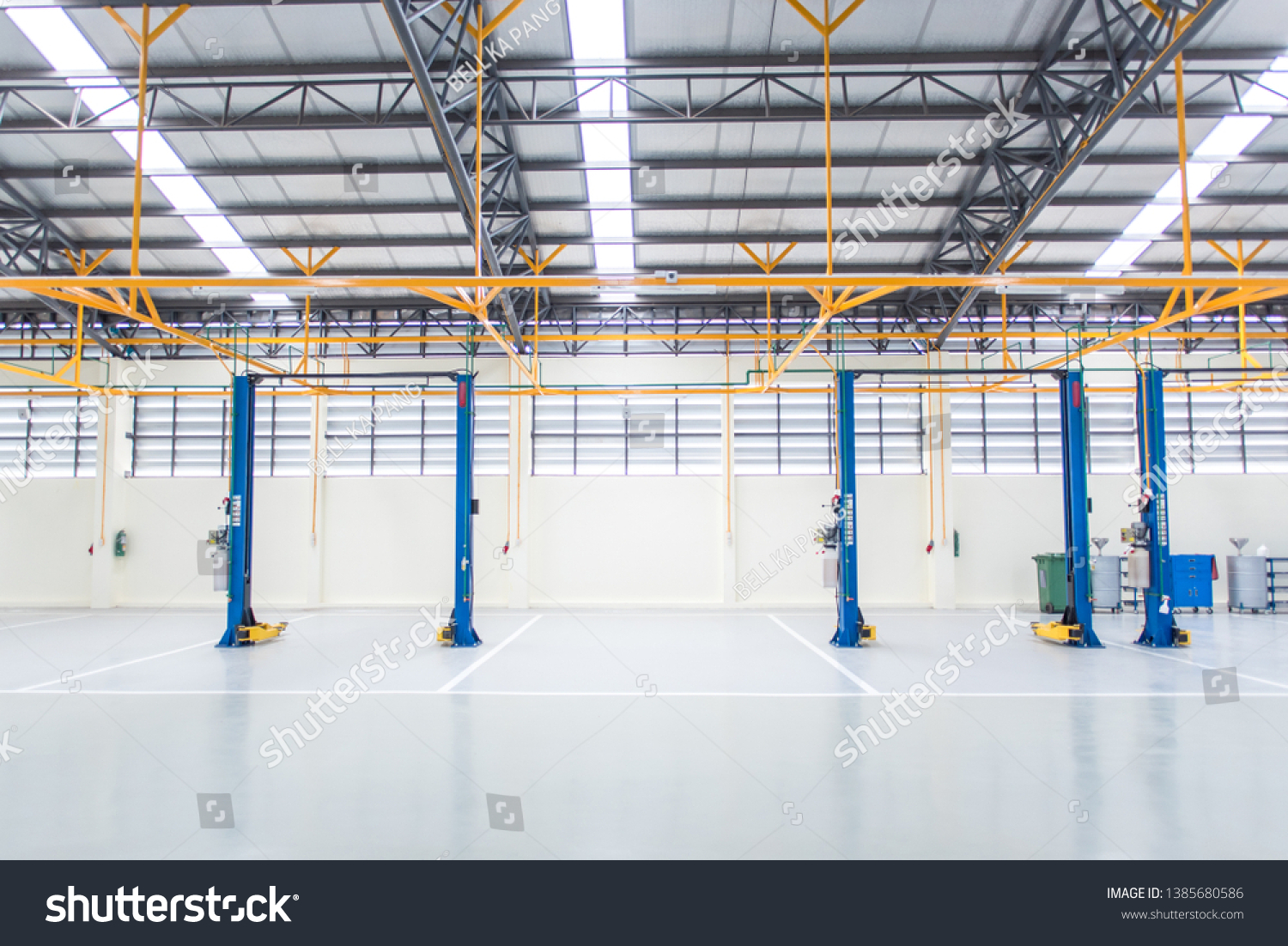 The electric lift for cars in the service put on the epoxy floor in new car factory service , Car repair service center blurred  background for industry  #1385680586