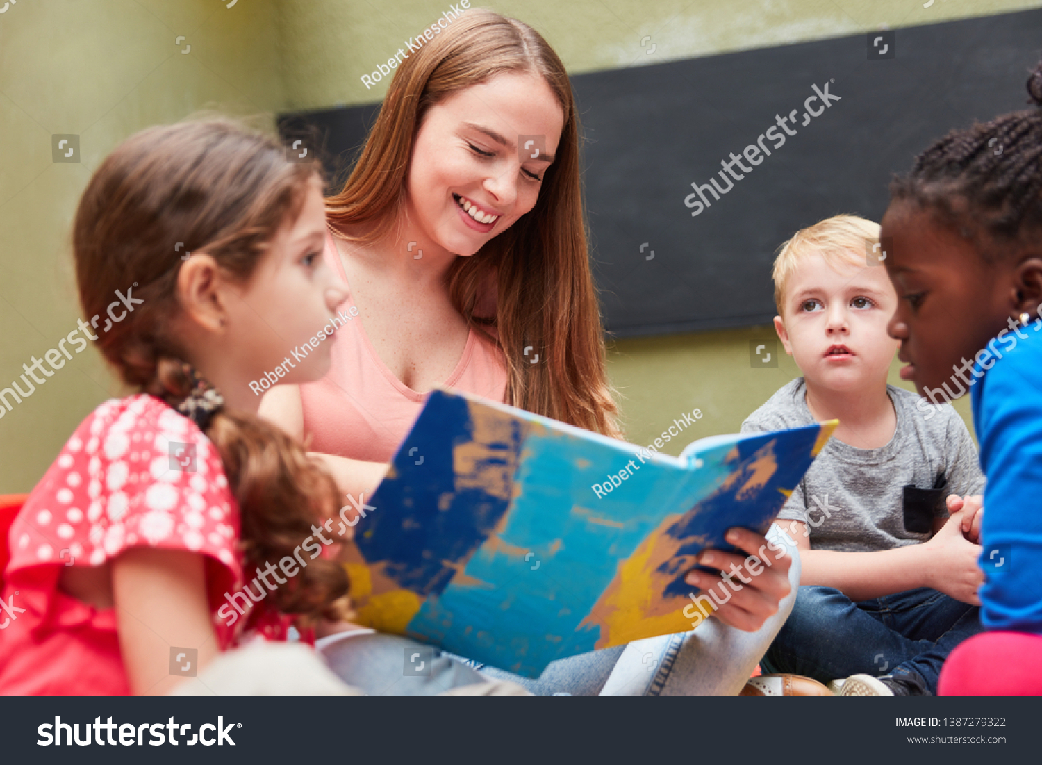 Group of children and educators reading from a children's book or storybook #1387279322
