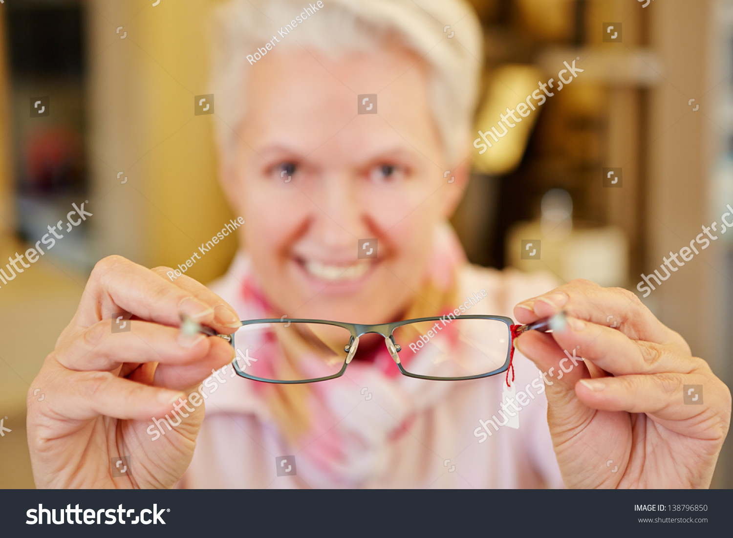 Smiling senior optician holding new glasses in her hands #138796850