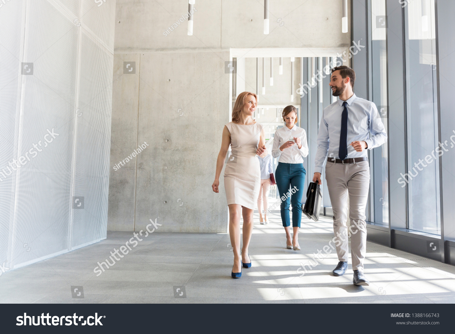 Business professionals talking while walking in office corridor #1388166743