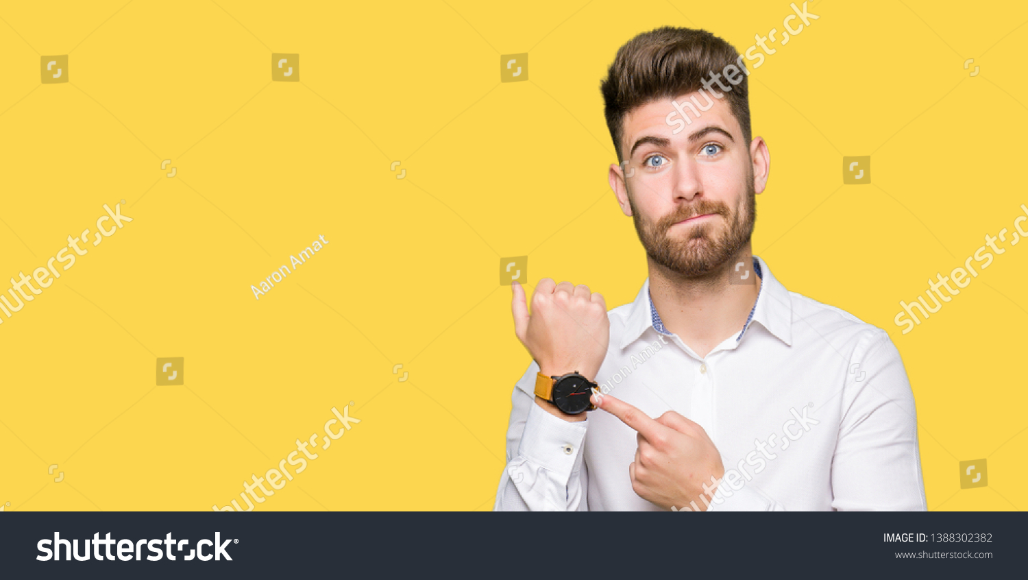 Young handsome business man In hurry pointing to watch time, impatience, upset and angry for deadline delay #1388302382