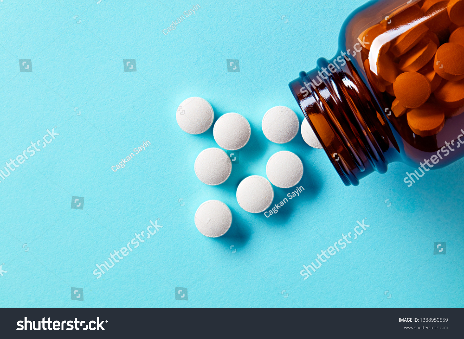 White medical pills and tablets spilling out of a drug bottle. Macro top down view with copy space.  #1388950559