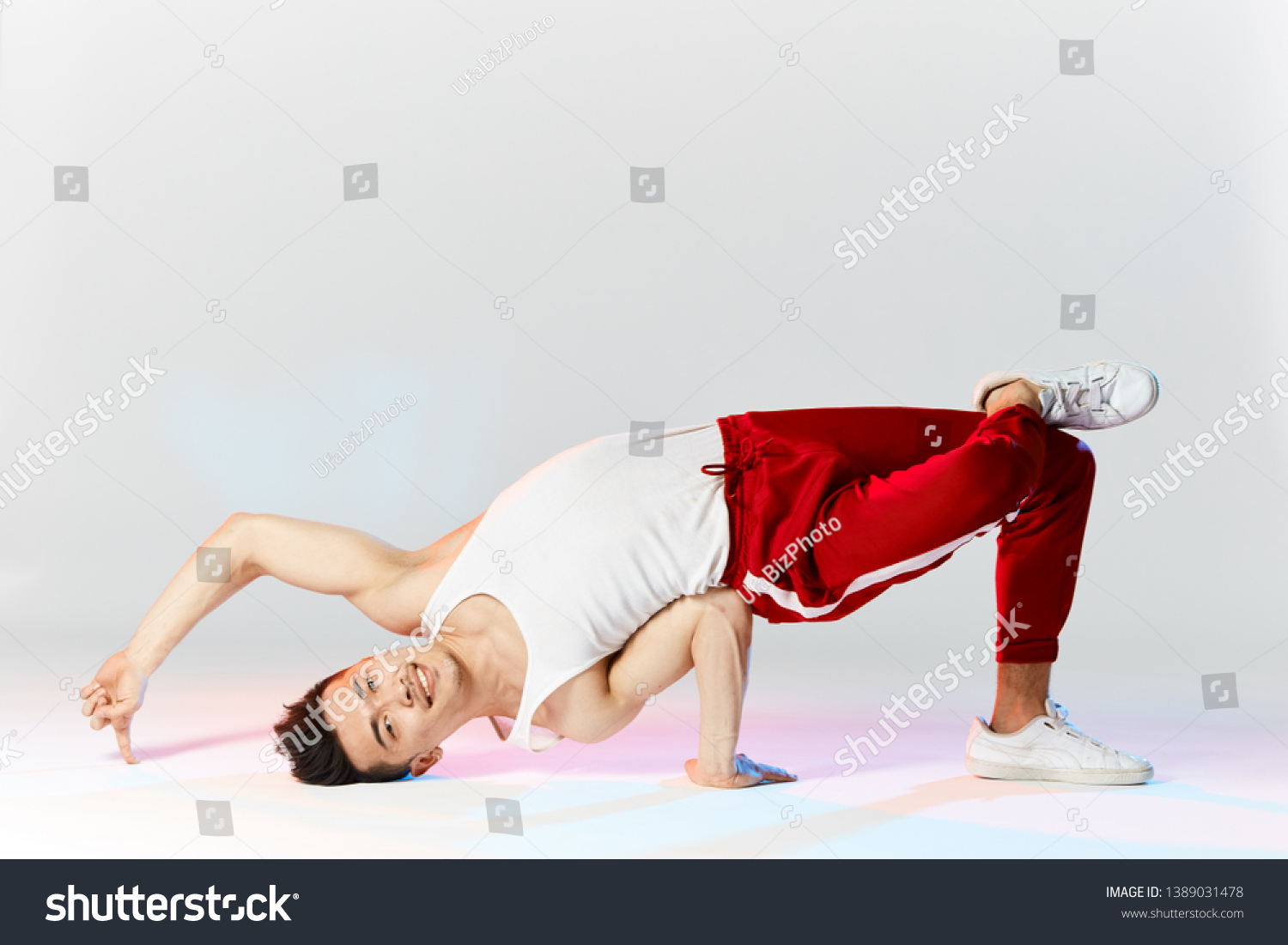 Asian male hip hop dancer or bboy freezes in Air Baby pose on the hand posing over white studio background #1389031478
