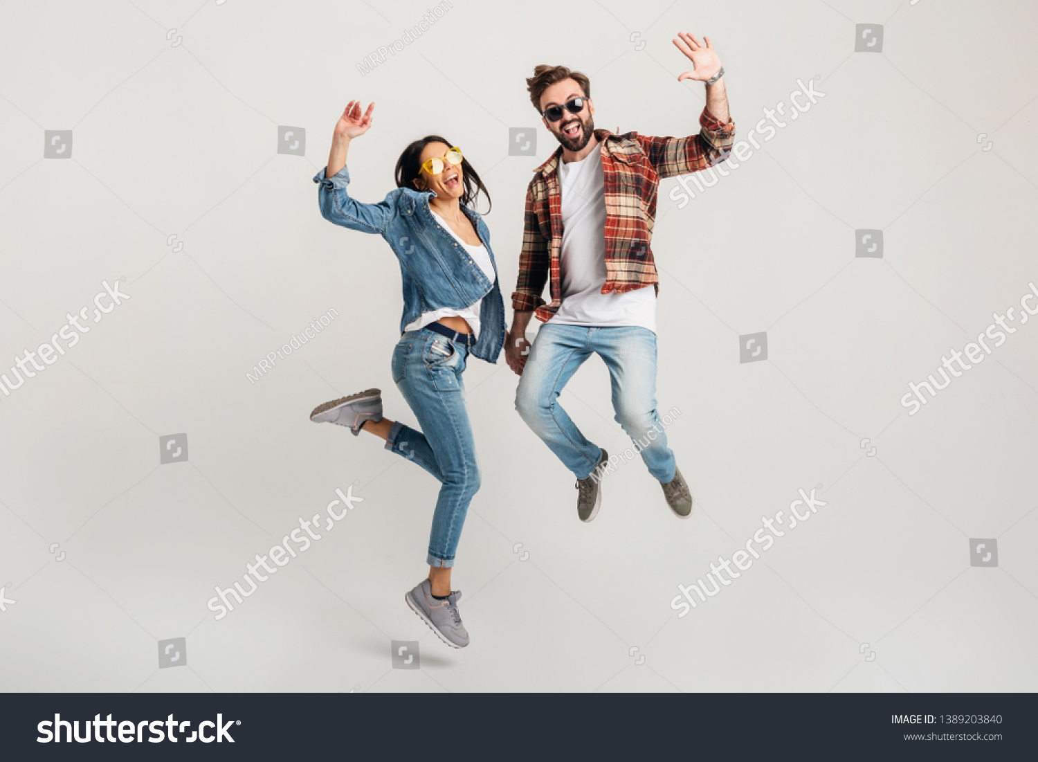 happy smiling couple isolated active jumping on white studio background, stylish mand and woman in casual denim hipster outfit wearing shirt and sunglasses having fun together, dating friends #1389203840