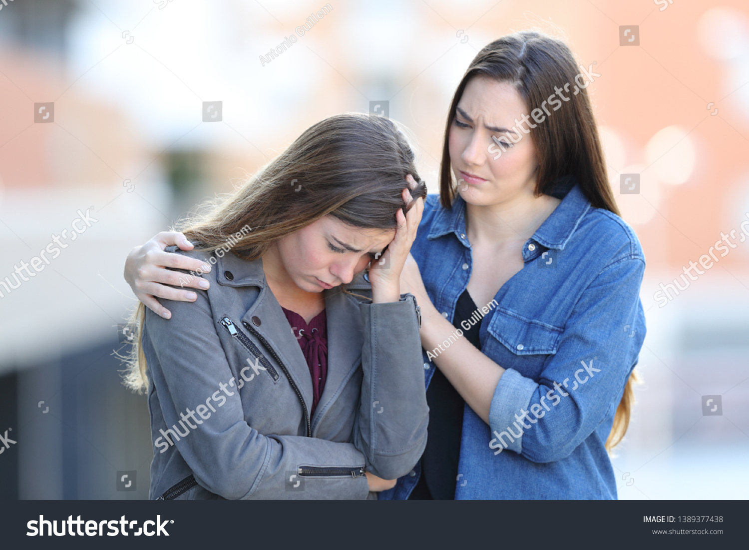 Worried woman comforting her sad friend who is complaining in the street #1389377438