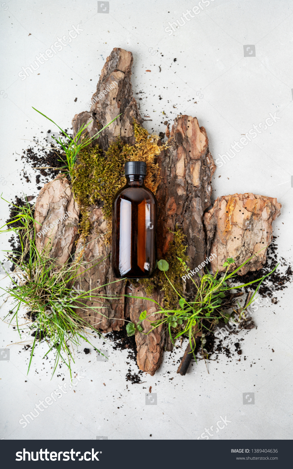 Environmentally clear nature concept background. Composition with glass bottle of shampoo over bark tree, moss and earth with grass for organic cosmetic products on white with copy space. #1389404636