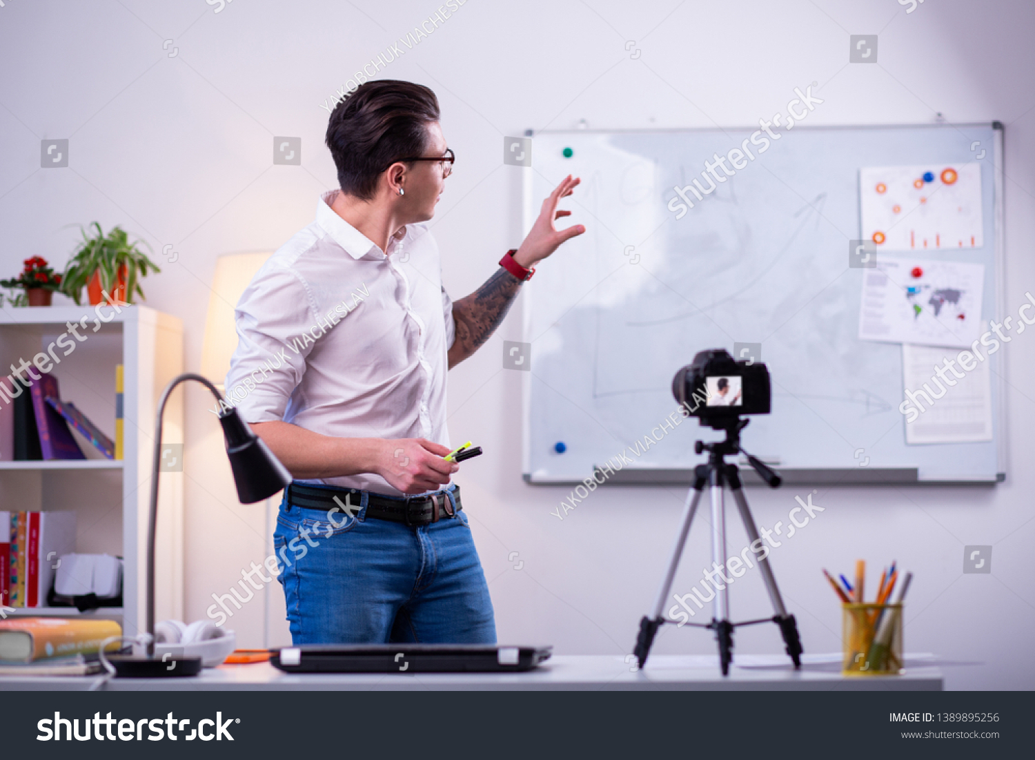 Professional science blogger. Expressive dark-haired man wearing neat white shirt and pointing on the desk with graphics #1389895256