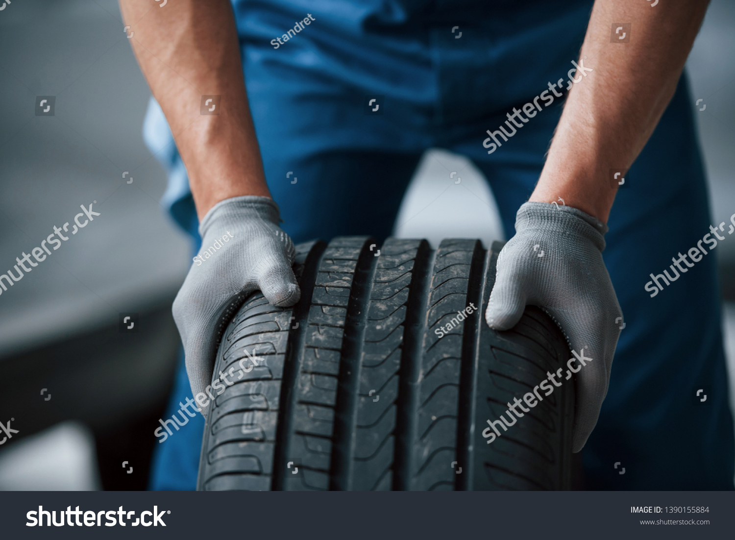 Dirt on the wheel. Mechanic holding a tire at the repair garage. Replacement of winter and summer tires. #1390155884