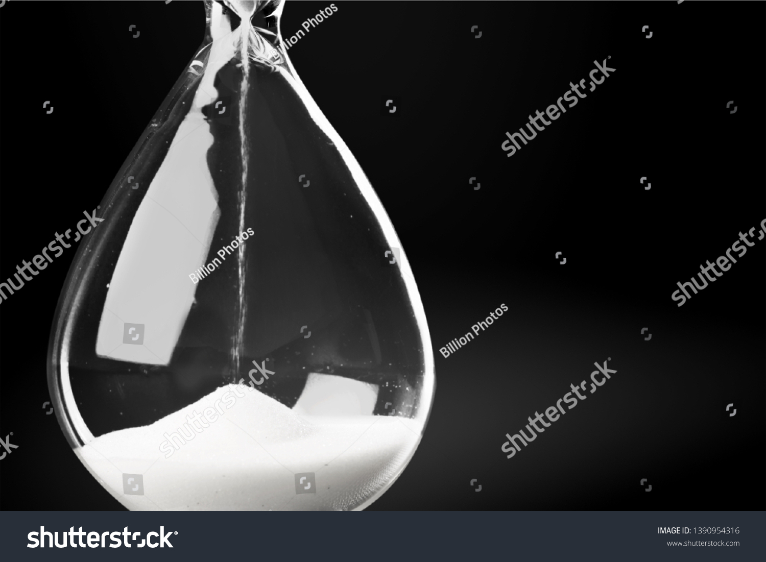 Hourglass as time passing concept for business deadline, urgency and running out of time. Sandglass, egg timer on dark background showing the last second or last minute or time out.  With copy space #1390954316