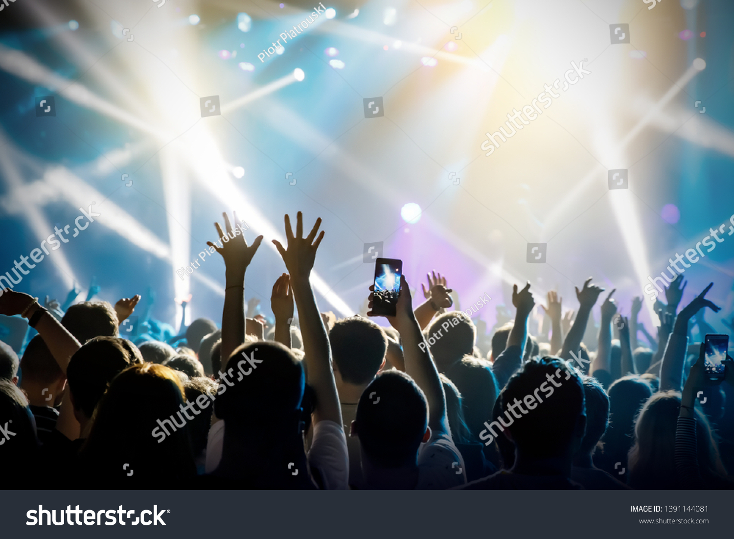 Raised hands in honor of a musical show on stage, People in the hall #1391144081
