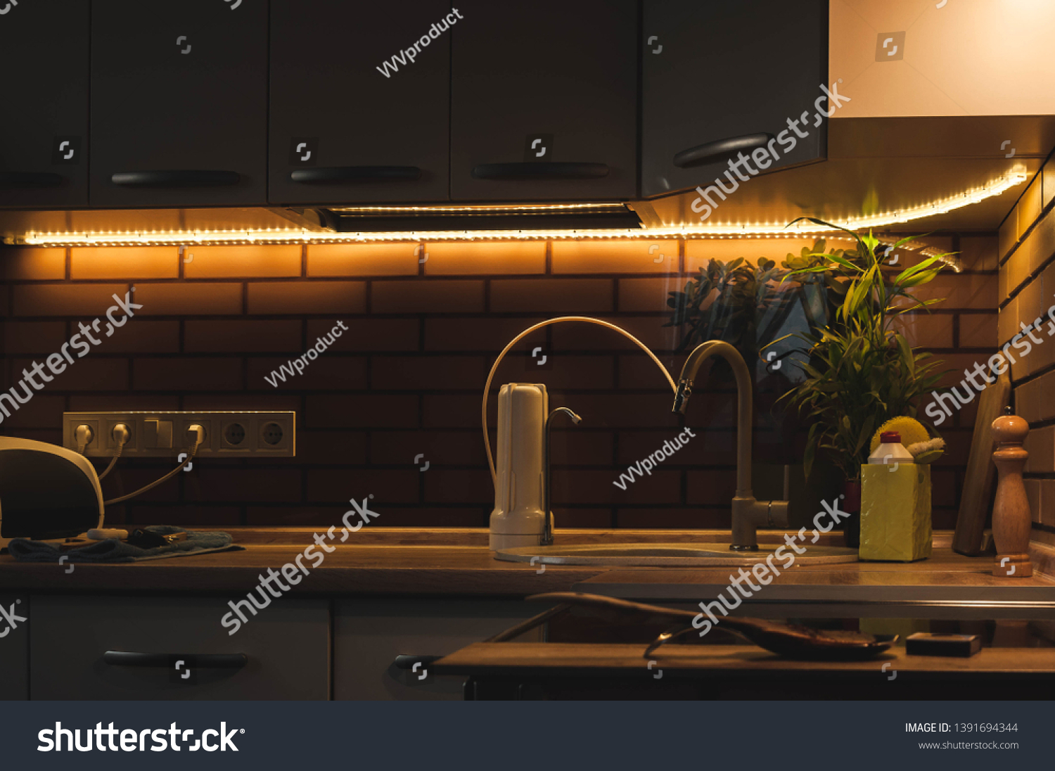 Evening life in a country house in the kitchen with a pleasant warm lighting. Modern interior compact kitchen. LED strip with base. Portable drinking water filter with replaceable cartridges. #1391694344