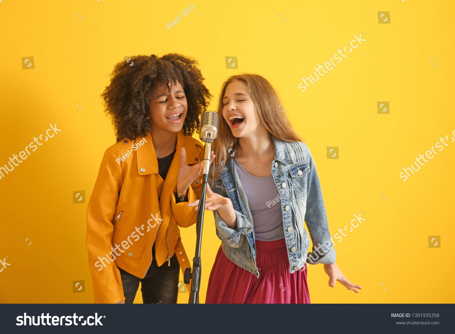 Teenage girls with microphone singing against color background #1391935358