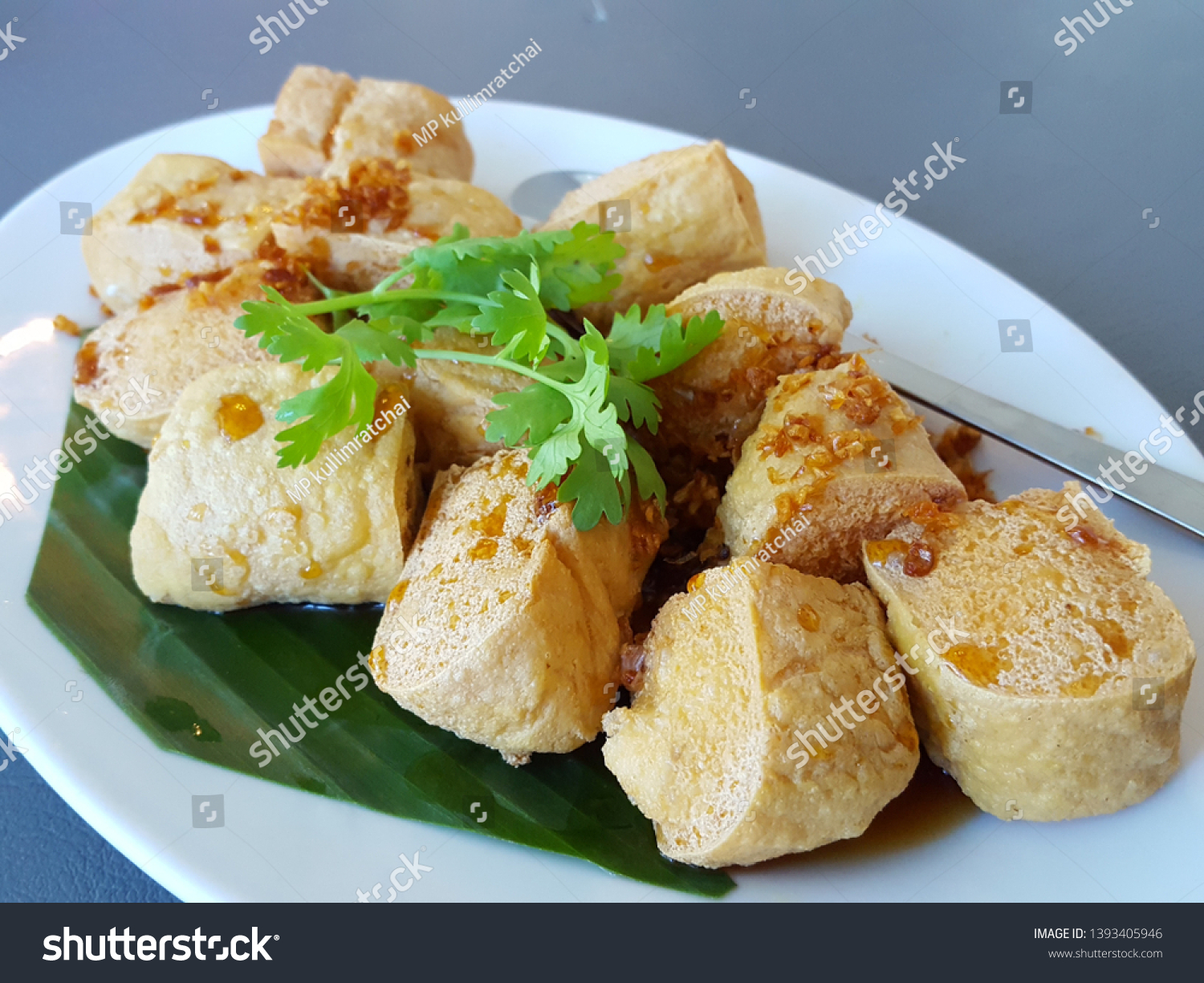 Asian food Tofu simmered in soy sauce with deep fried garlic and coriander. Traditional fried tofu on banana leaf.Asian food concept,soft focus,Select focus #1393405946