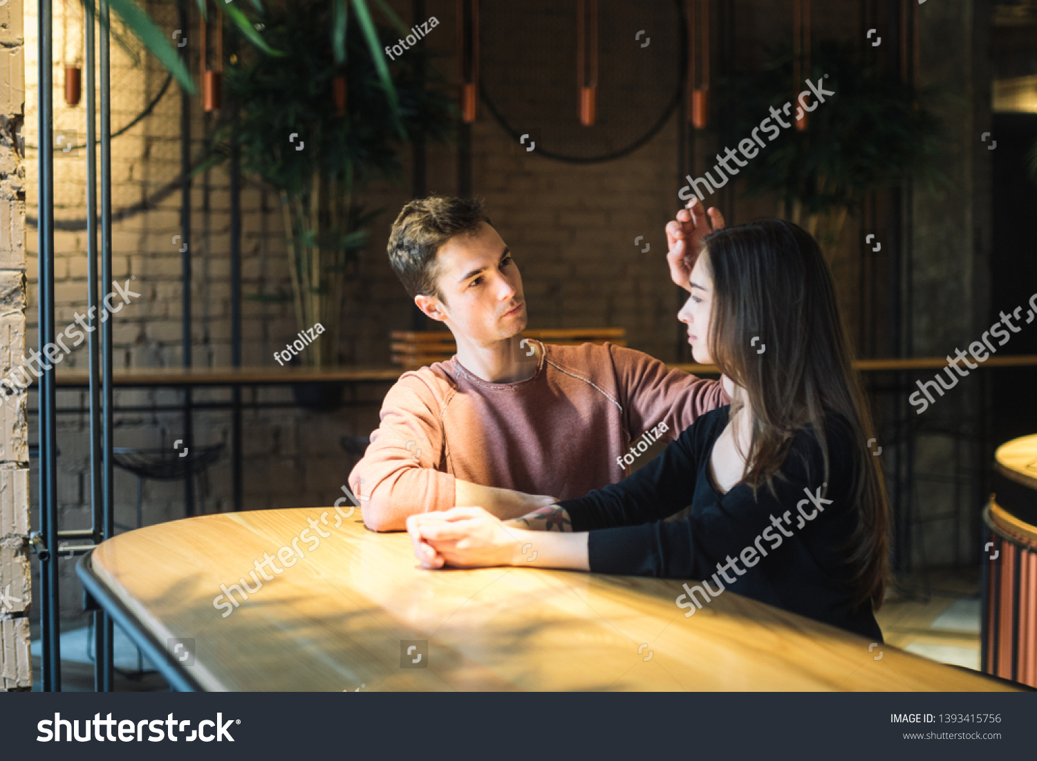 Theme love and holiday Valentines Day. couple of college students together in Caucasian heterosexual lovers winter inside the cafe sit at empty table embrace. Emotion happiness and love. #1393415756