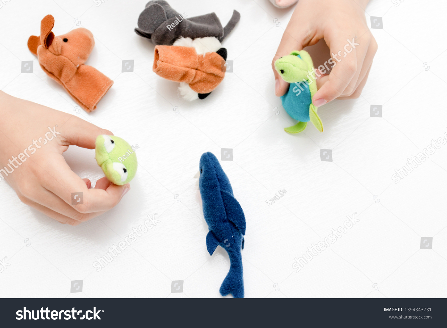 A caucasian boy playing finger puppets, toys, dolls - figures of animals, heroes of the puppet theatre put on fingers of human hand. #1394343731