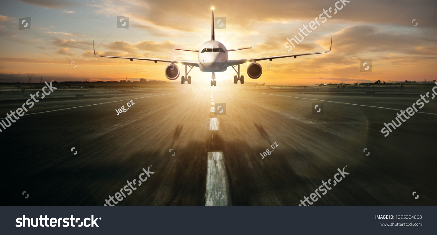 Commercial jetliner landing on runway. Modern and fastest mode of transportation. Dramatic sunset sky on background #1395304868