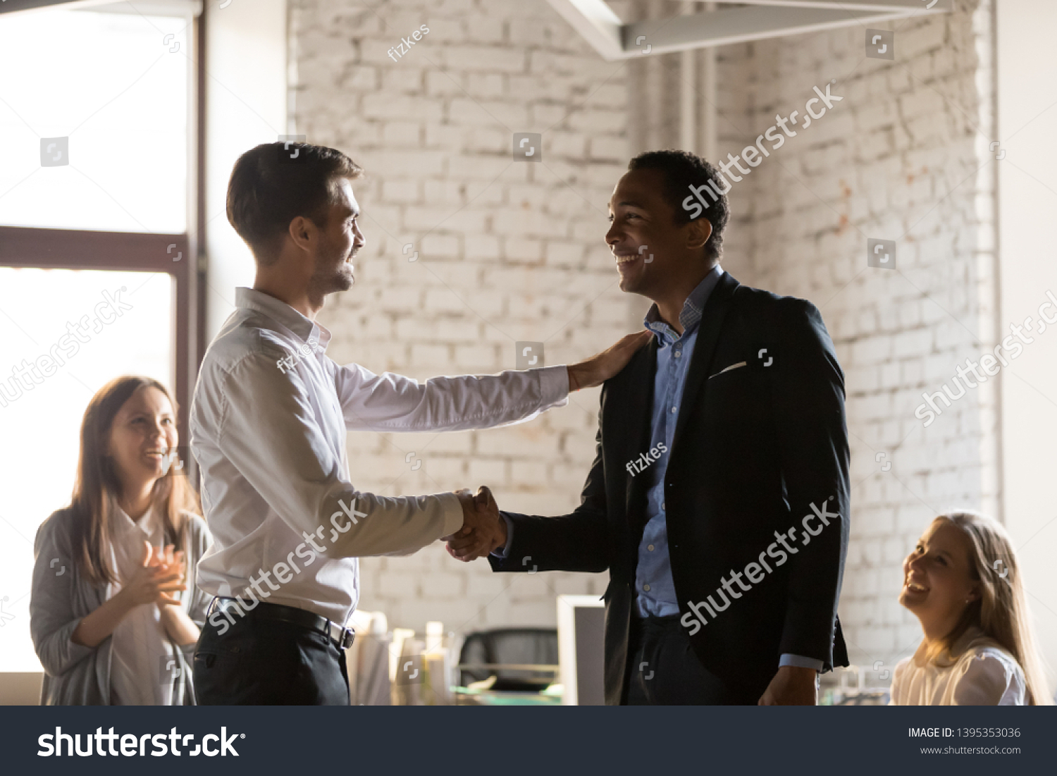 Diverse team gather at office, young boss shaking hands congratulate african employee with promotion and reward. Appreciation and gratitude, new member staff first impression, award and bonus concept #1395353036