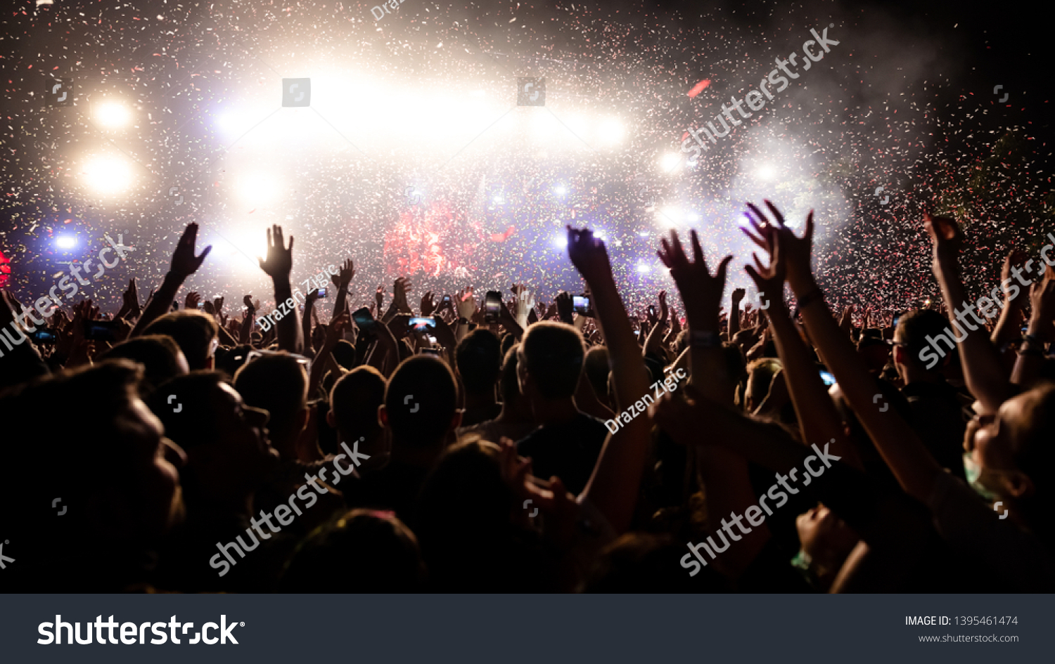 Crowd of people having fun while watching confetti fireworks at music festival. Copy space. #1395461474