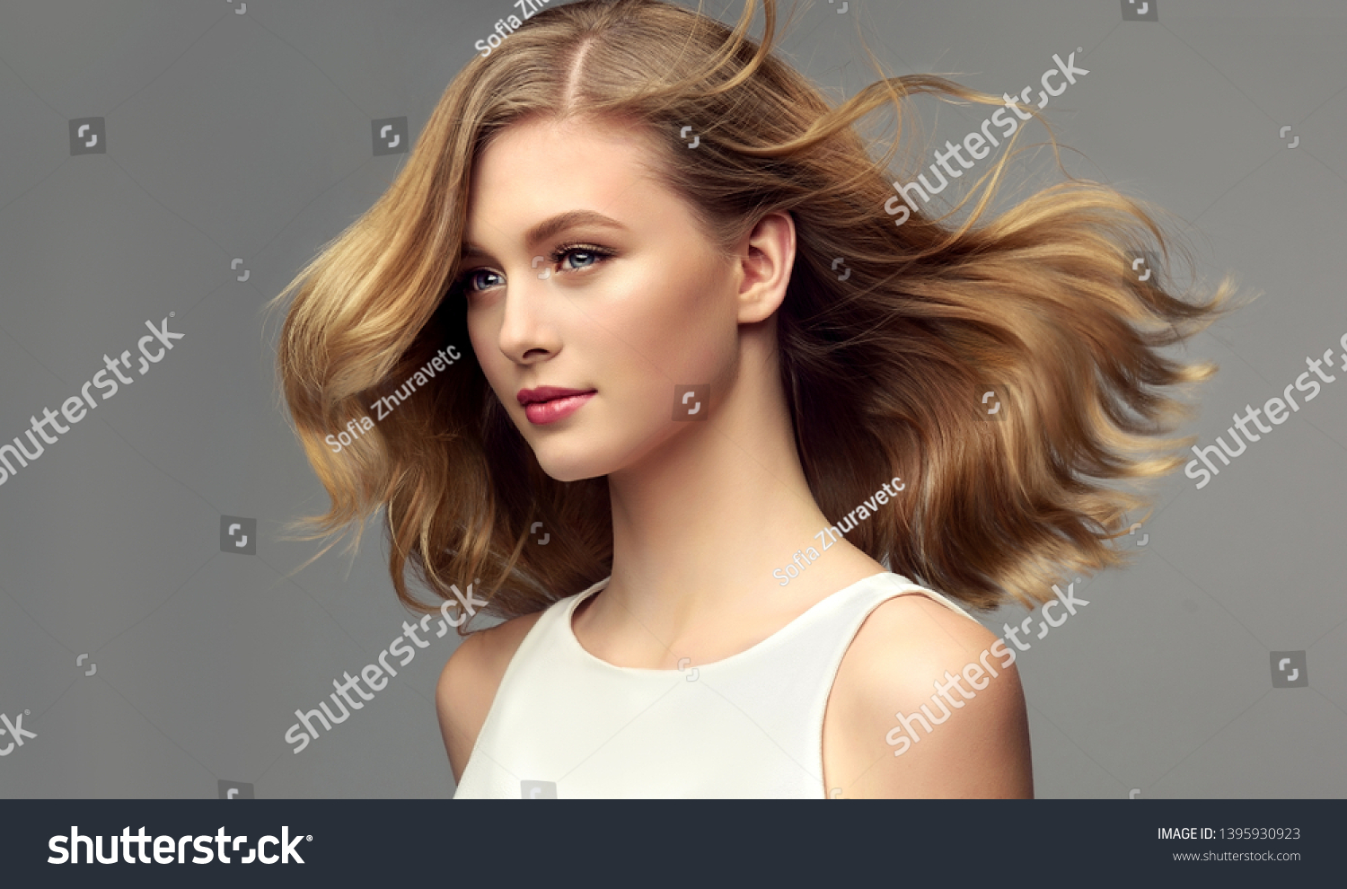 Blonde woman with curly beautiful hair  on gray background. The girl with a pleasant smile. Short haircut . Bob hairstyle
 #1395930923