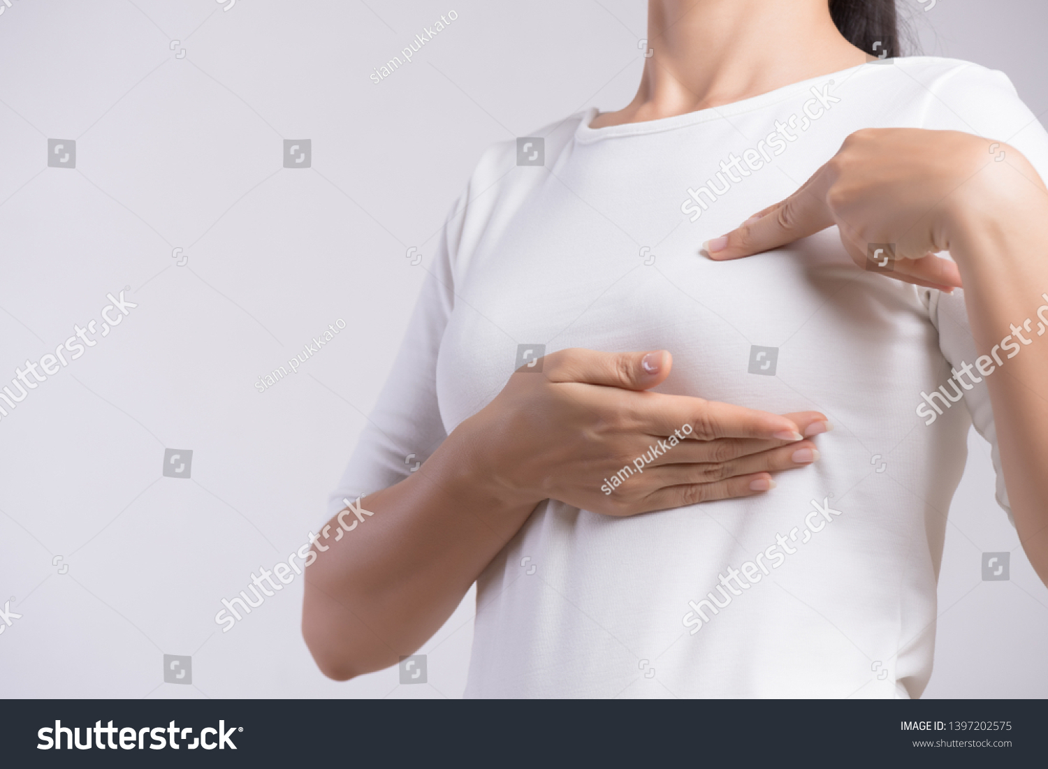 Woman hand checking lumps on her breast for signs of breast cancer on gray background. Healthcare concept. #1397202575