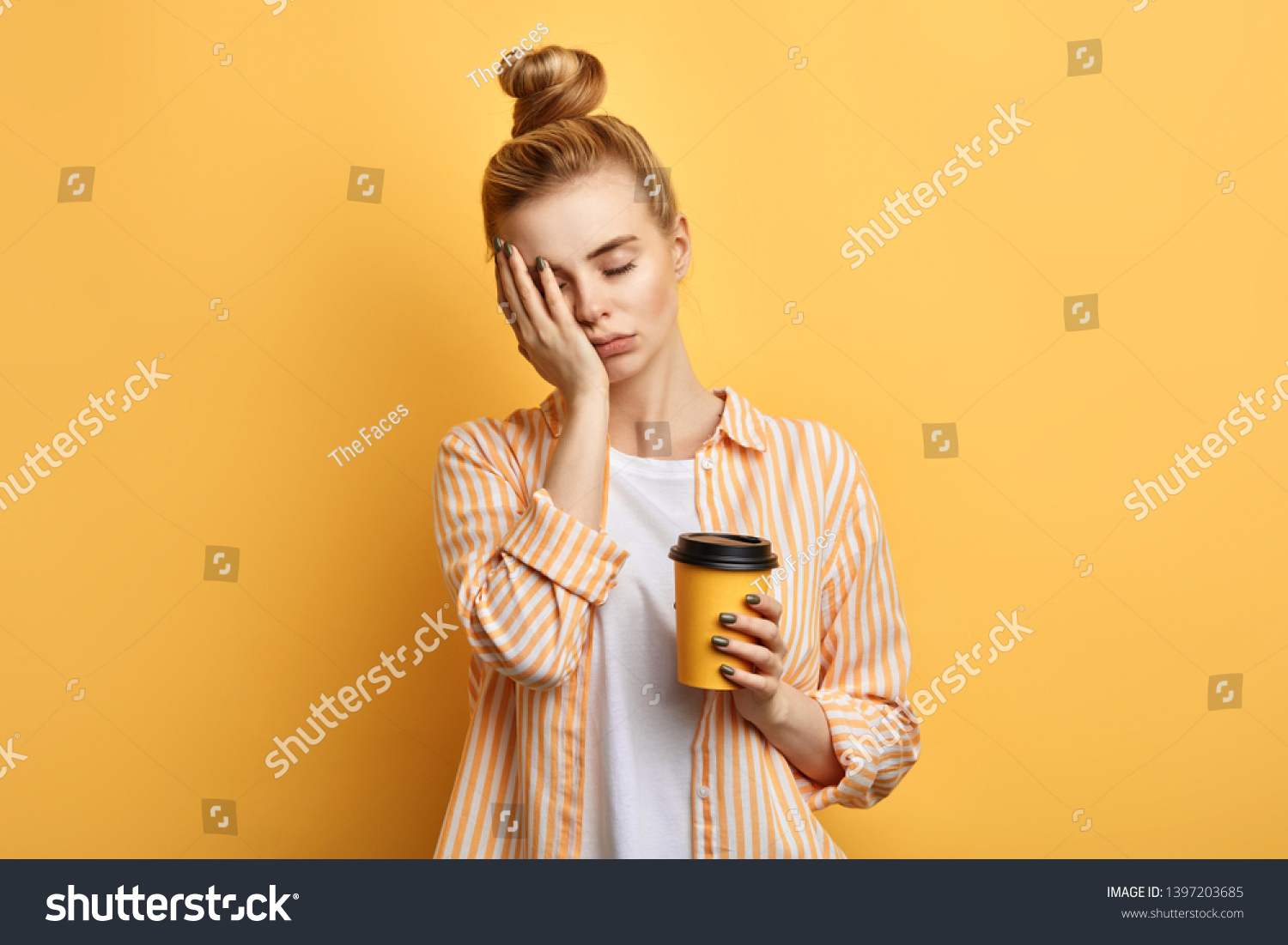 Tired sleepy woman holds a cup of coffee, has sad expression, closes eyes, cannot wake up in the morning and go to work. difficult, hard monday. isolated yellow background #1397203685