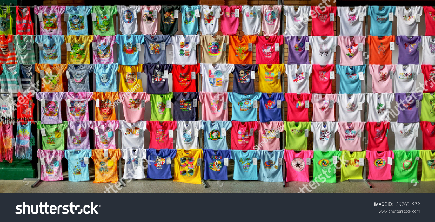 Sevilla, Spain - February 13, 2019: Collection of Summer colorful t-shirts with funny screen printings sold at souvenir shop in Seville, Spain. #1397651972