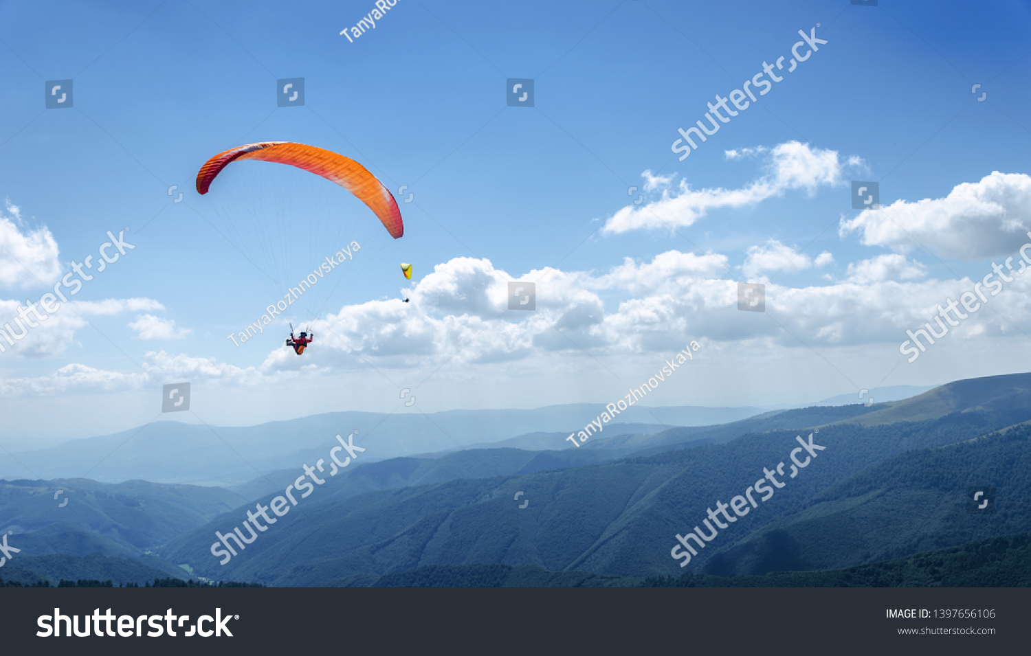 Paraglider in the blue sky. The sportsman flying on a paraglider. #1397656106