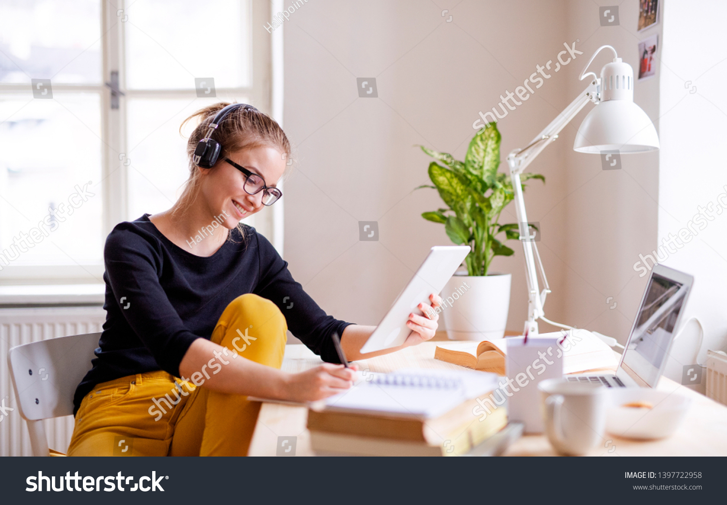 A young female student sitting at the table, using tablet when studying. #1397722958