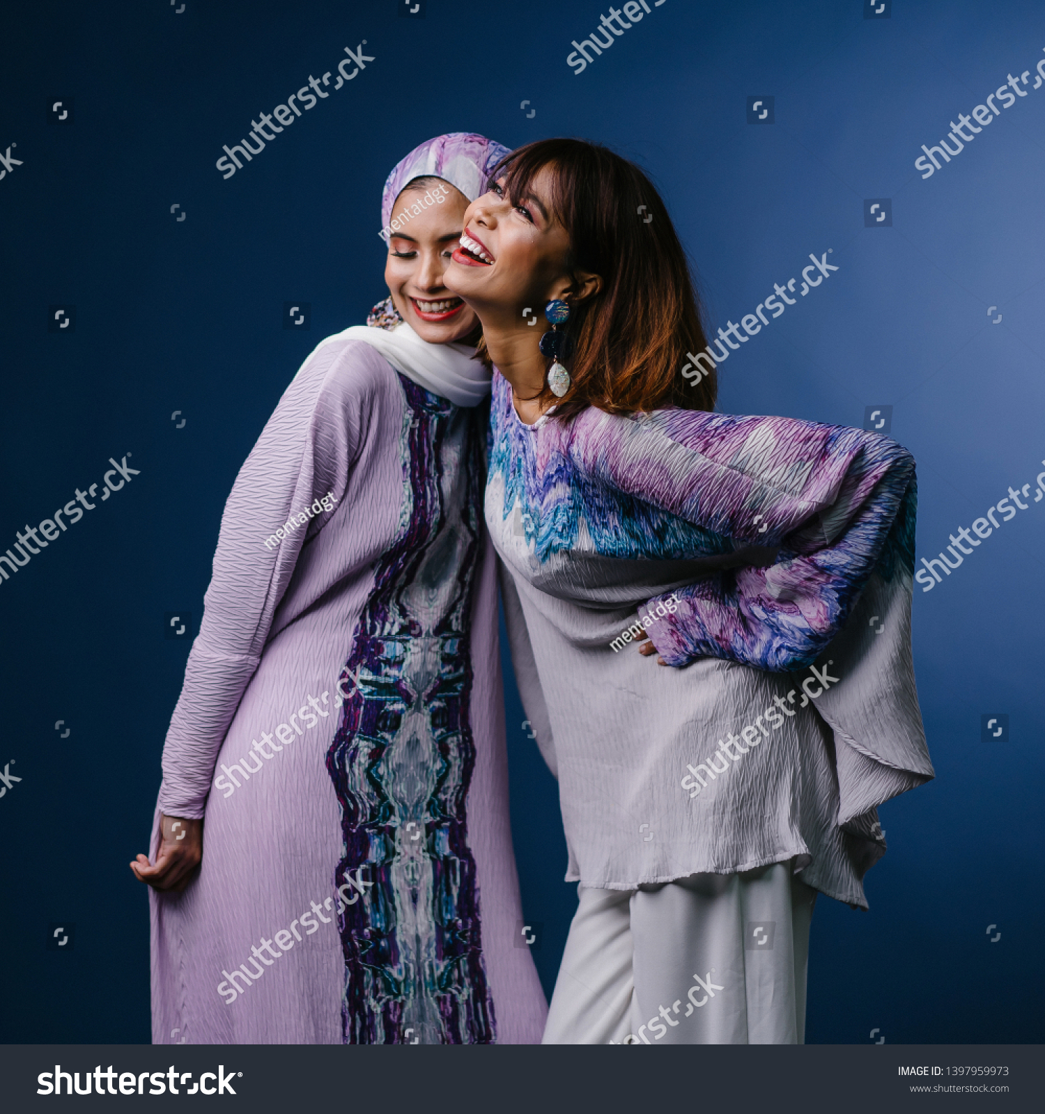 Portrait of two Middle Eastern Muslim women in festive ethnic Raya clothing posing in a studio. They are both young, attractive and beautiful. The women are friends or relatives.  #1397959973