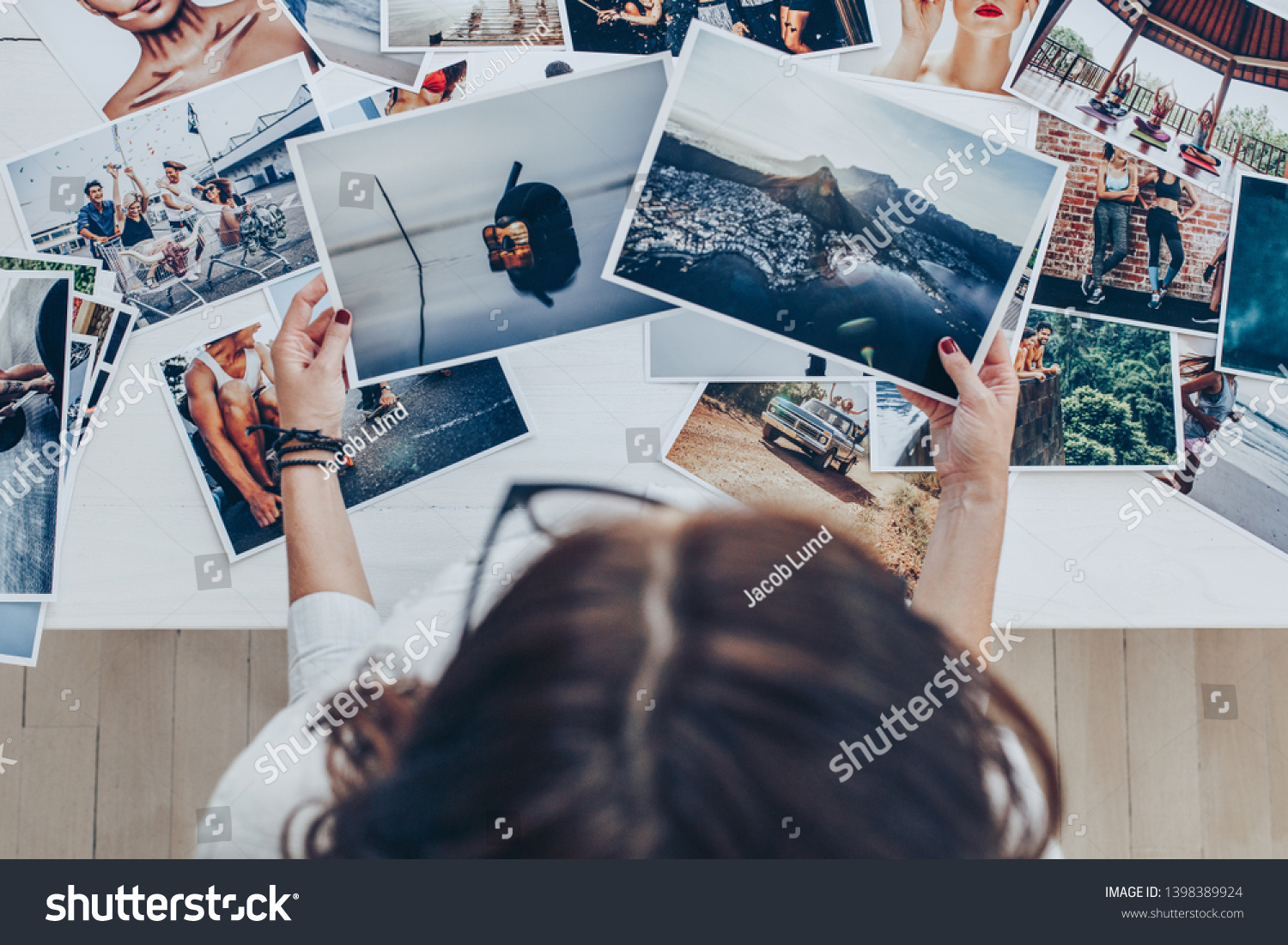 Top view of a woman photographer working in studio. Female photographer checking image prints. #1398389924