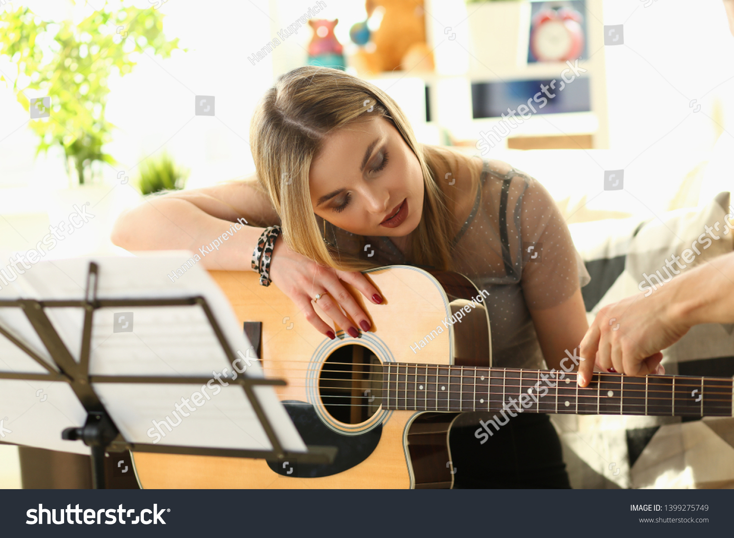Guitar Playing Lesson Music Education Concept. Woman Practice while Sitting on Sofa. Man Hand Touching Strings Showing Chords. Beautiful Blonde Listening Carefully. Inspiration for Musical Performance #1399275749