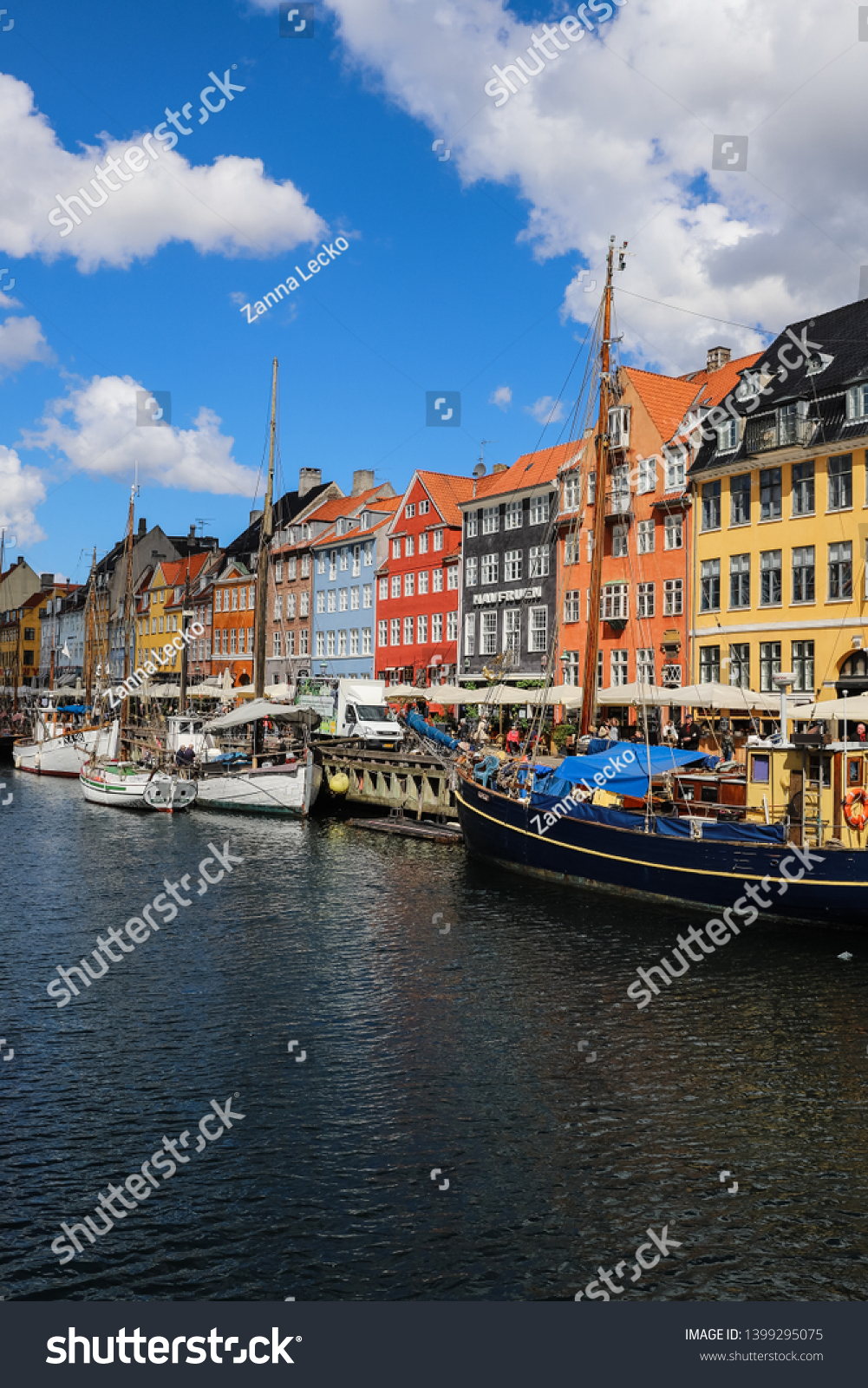 COPENHAGEN, DENMARK - May 13, 2019 : Colorful historical houses and old wooden boats located on the canal of famous Nyhavn port, on a sunny day #1399295075