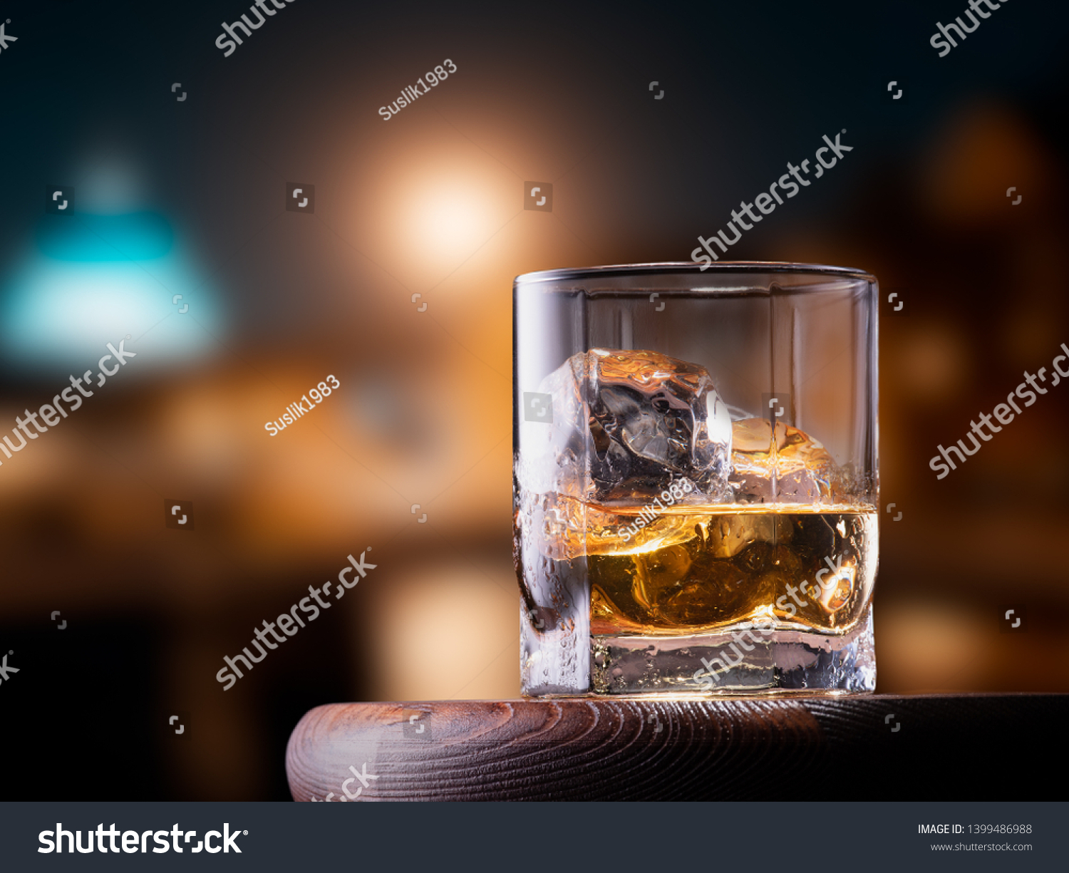 Glass of whiskey with ice cubes on the wooden table with city view background #1399486988