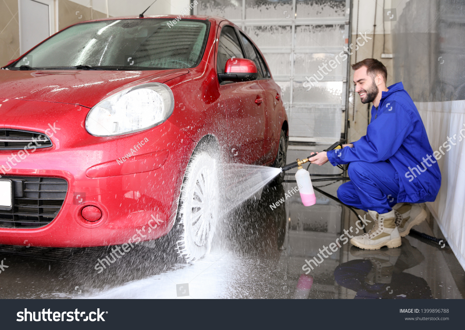 Worker cleaning automobile with high pressure water jet at car wash #1399896788