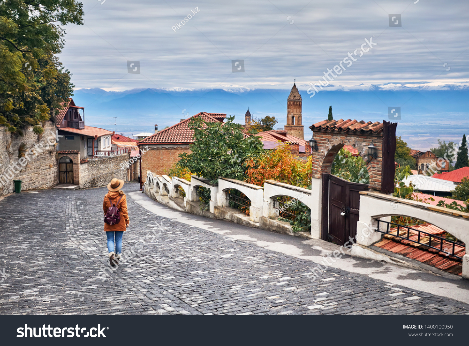 Tourist woman in hat with backpack at the street of Signagi town in Georgia #1400100950