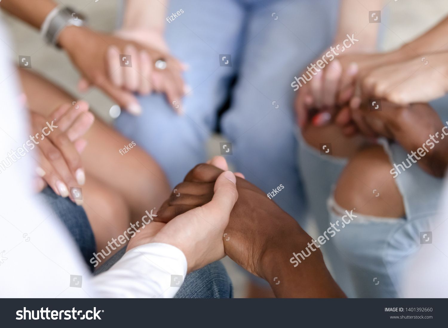 Close up of multiracial people sit in circle holding hands show mutual support and understanding at therapy session, diverse men and women gather give help at group psychological treatment #1401392660