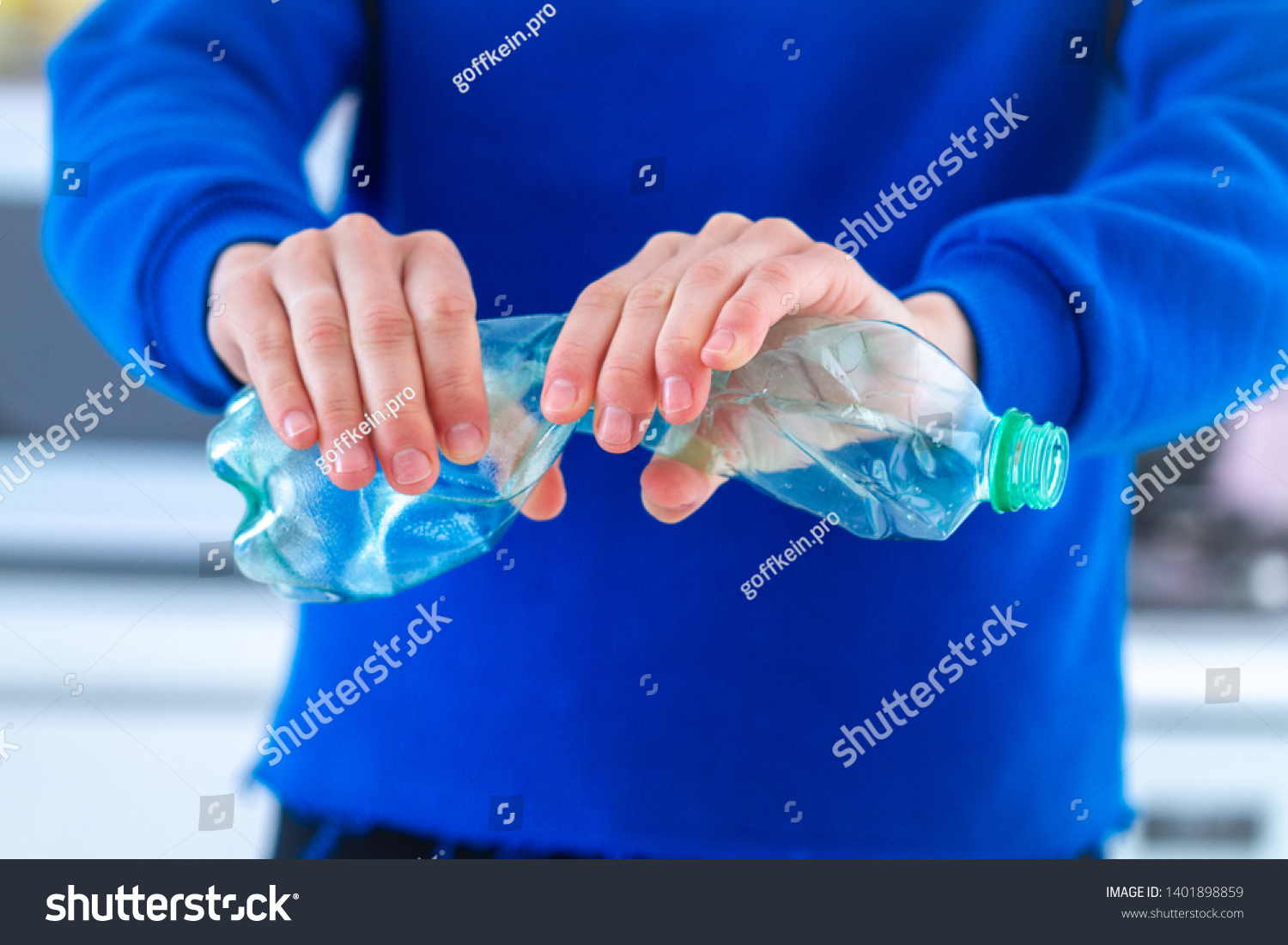 Woman holding used crushed and crumpled mineral water and fizzy drinks bottles at kitchen at home. Ecology problems and ecology care #1401898859