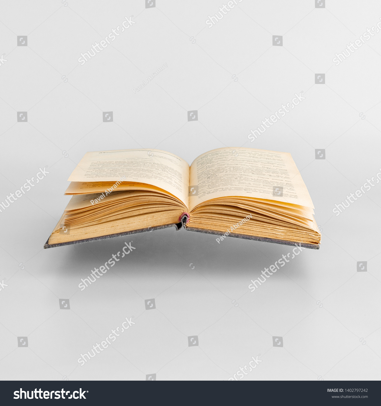 Levitating open old book on white background.  Minimal concept. Copy space #1402797242