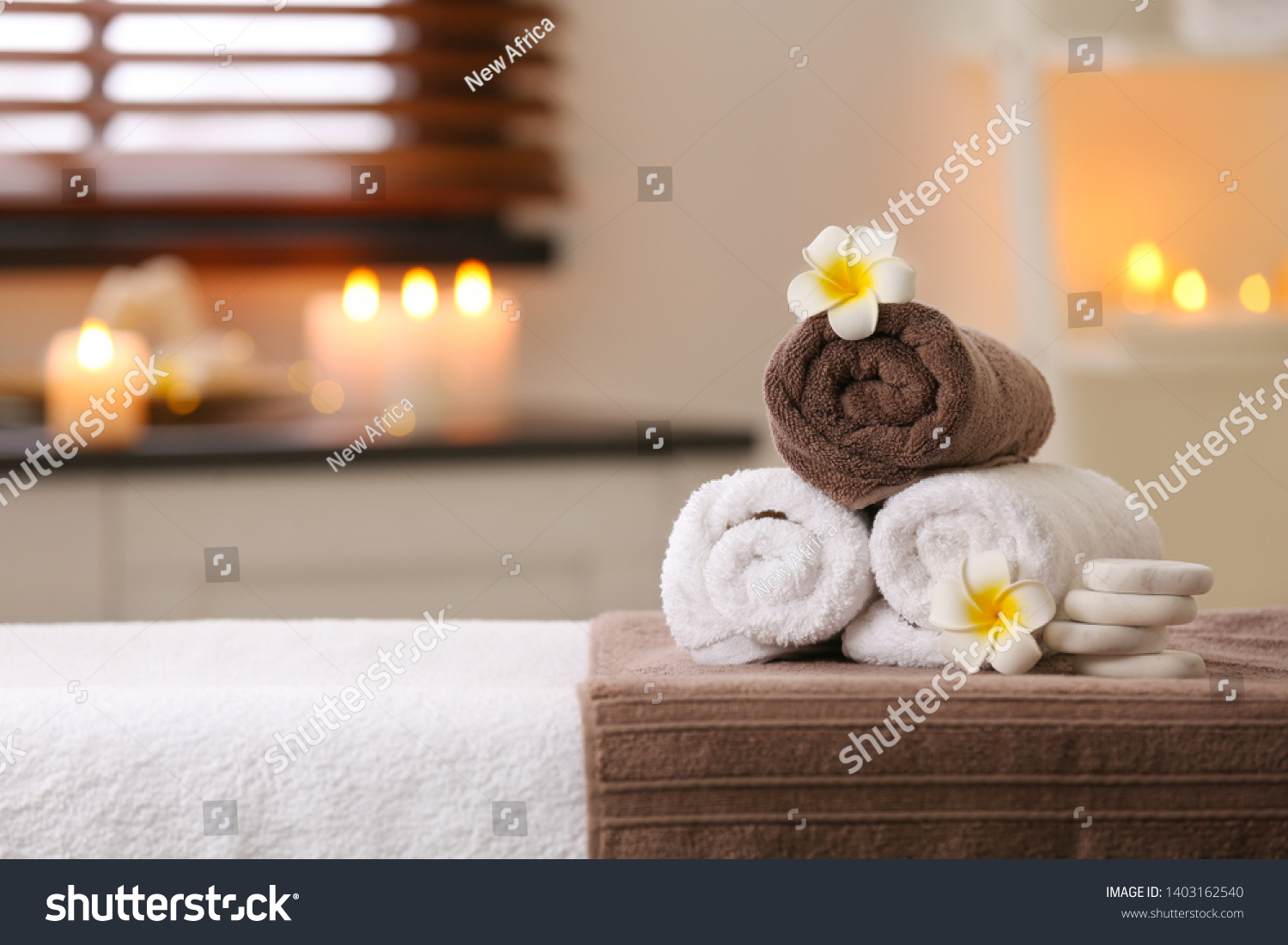 Composition with towels, flowers and stones on massage table in spa salon. Space for text #1403162540