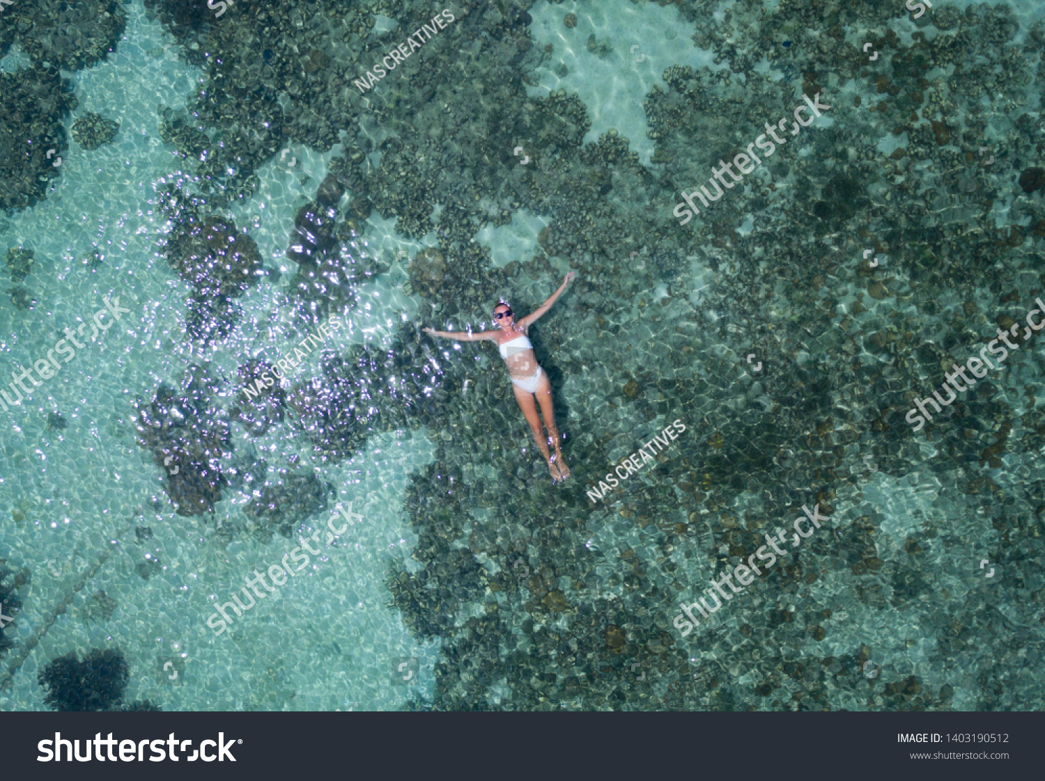 Aerial drone top view of woman floating in crystal clear sea water with coral reef #1403190512